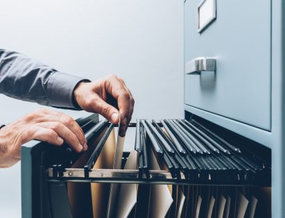 A man searching through a filing cabinet
