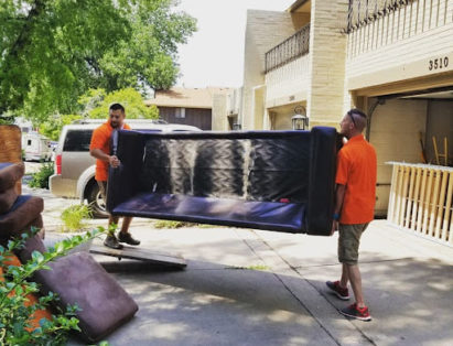 altitude hauling pros carrying old couch during junk removal job